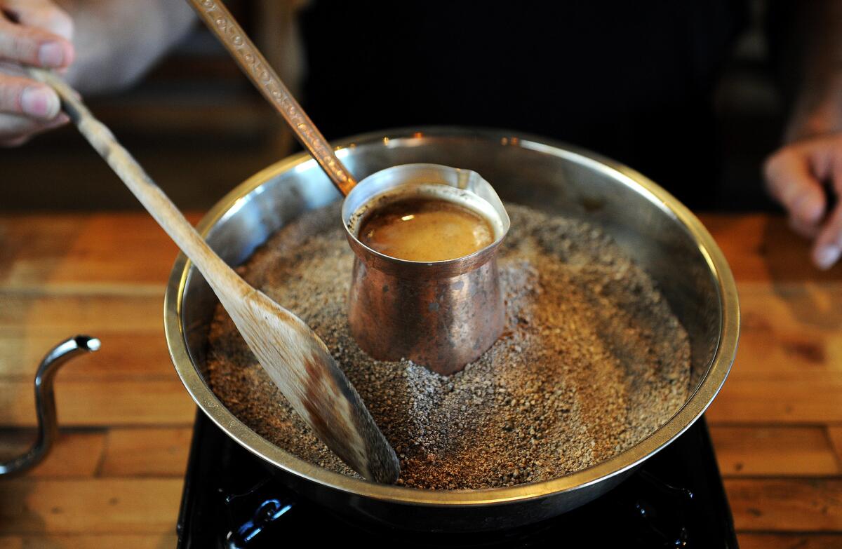 Stan Mayzalis makes jazzve-style coffee on a bed of hot sand at Doma Kitchen in Manhattan Beach.