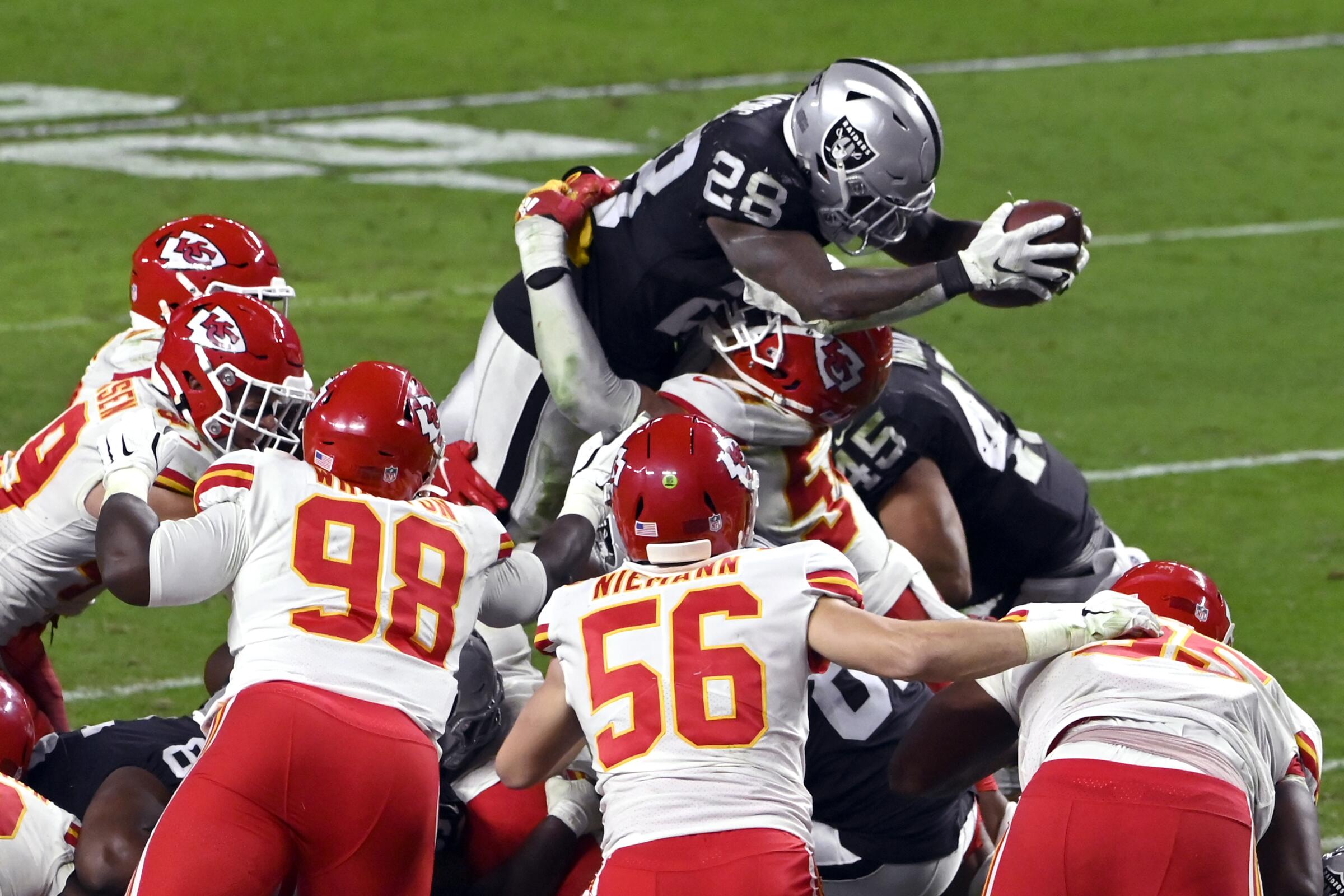 Las Vegas Raiders running back Josh Jacobs dives over the Kansas City Chiefs' defensive line to score a touchdown.