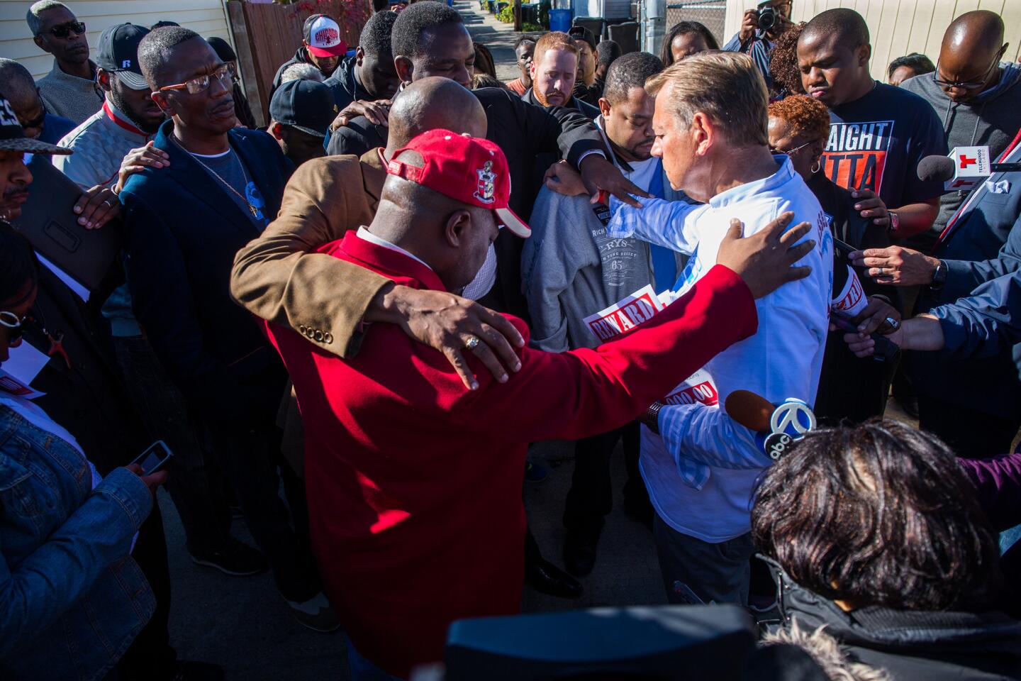 The Rev. Michael Pfleger, holding flier at right center, and members of St. Sabina Catholic Church pray Nov. 3, 2015, in the alley where 9-year-old Tyshawn Lee was fatally shot the day before in the 8000 block of South Damen Avenue, in Chicago's Gresham neighborhood.