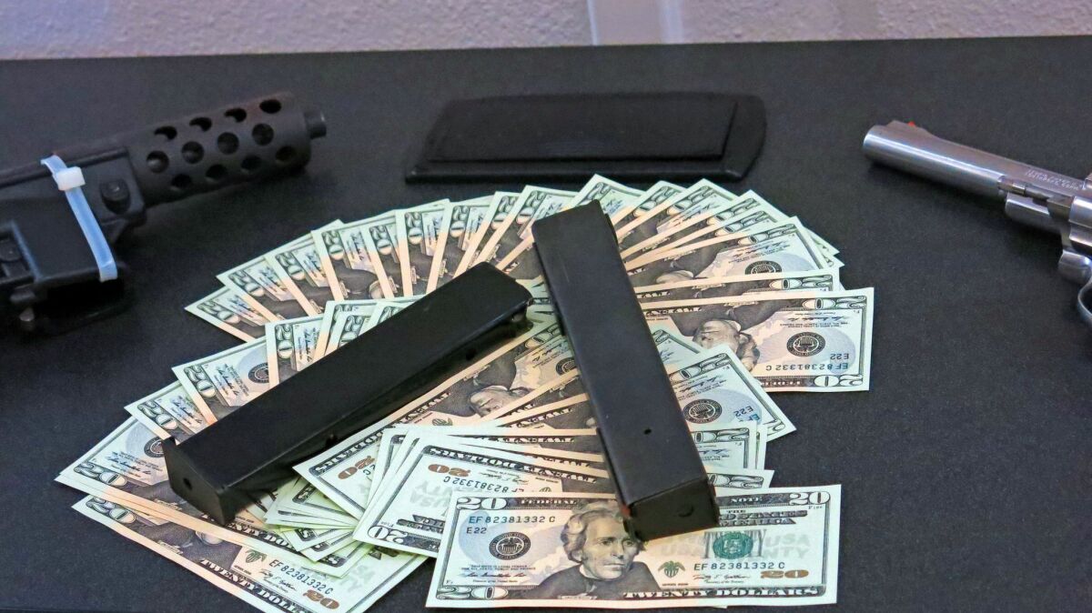 Counterfeit bills and weapons are displayed in Seal Beach.