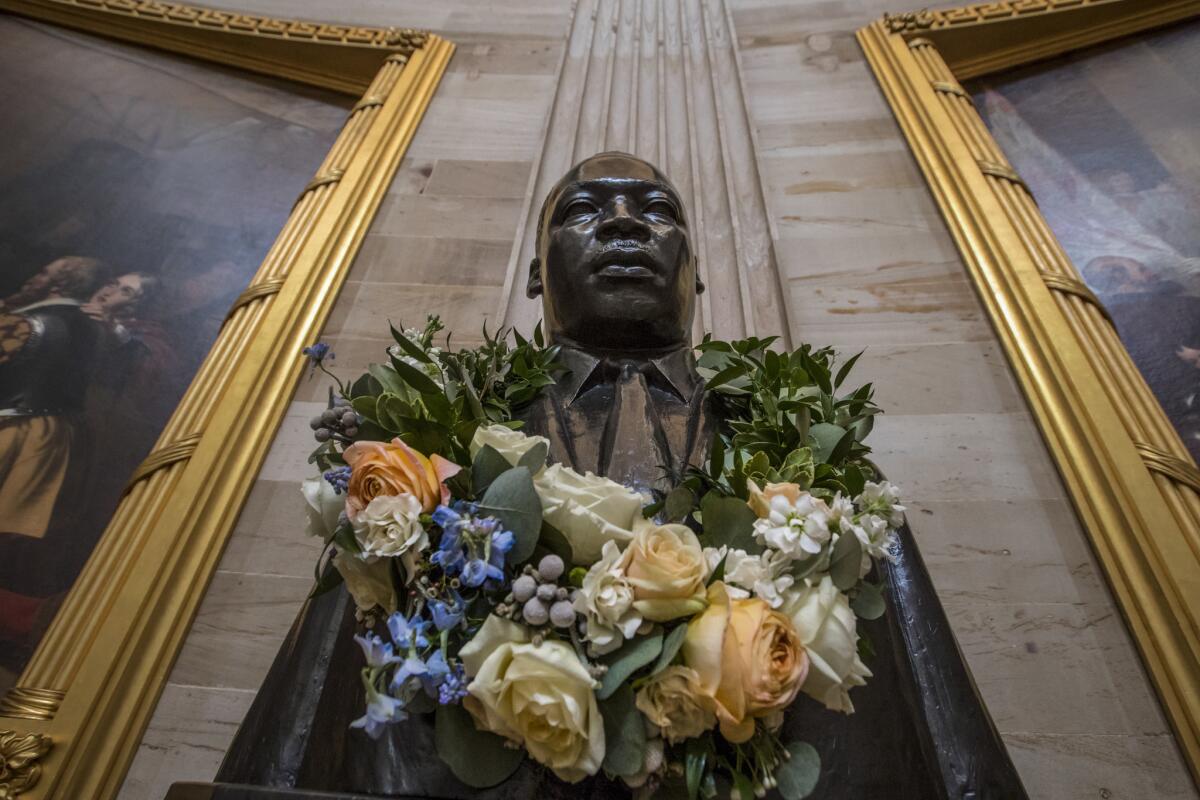 A representative of the Burbank Human Relations Council writes words of gratitude for participants in an MLK breakfast and to the VWF for hosting it. Above, the bust of the late civil rights leader is draped with a wreath of flowers to commemorate his birthday in the Capitol Rotunda in Washington, D.C. in this 2018 photo.