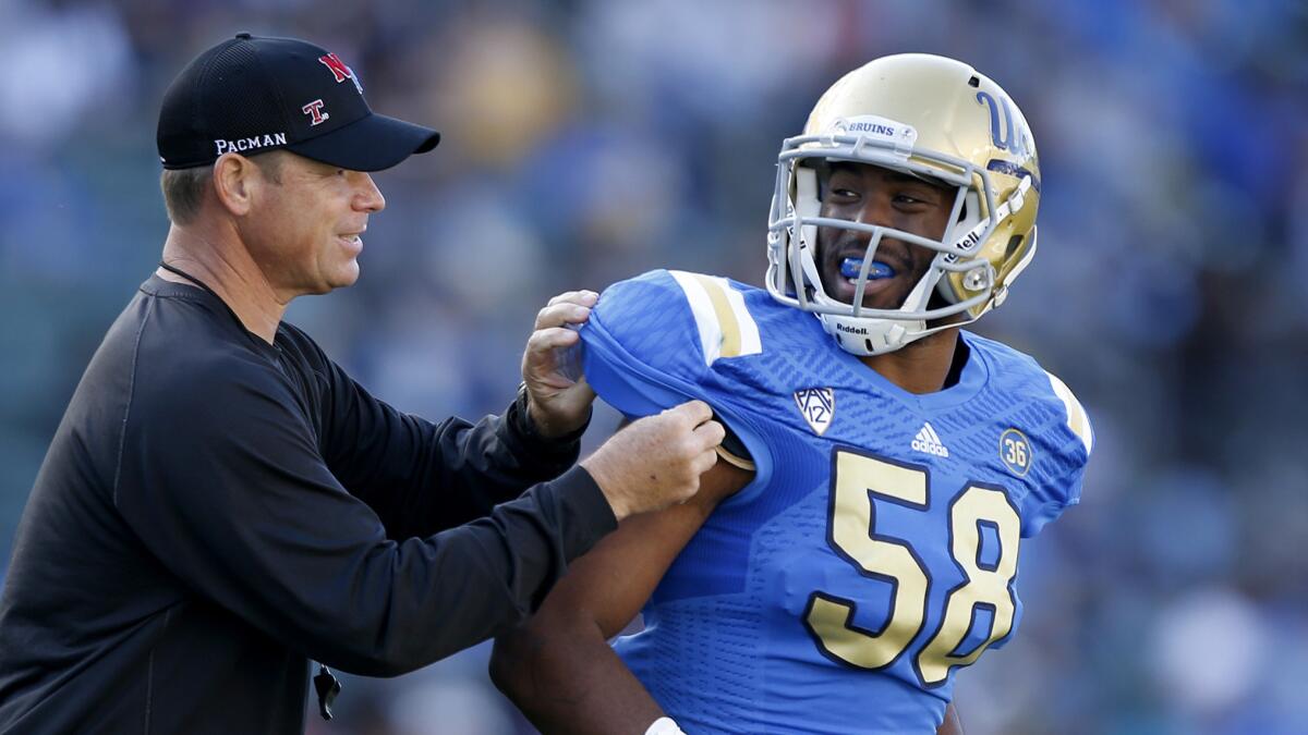 UCLA Coach Jim Mora helps linebacker Deon Hollins with his shoulder pad during the Bruins' spring game in April. UCLA defensive coordinator Jeff Ulbrich was pleased with Hollins' performance against Virginia.