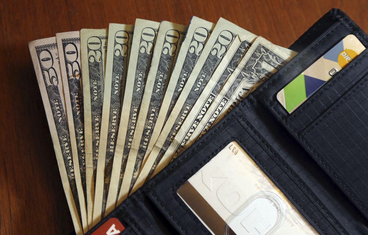 FILE - In this June 15, 2018, file photo, cash is fanned out from a wallet in North Andover, Mass. Mapping out planned expenses like vacations, holiday gifts and membership renewals in advance gives you time to save in smaller chunks. “Sinking” your funds into buckets created for each savings goal is one way to avoid feeling overwhelmed as the deadline approaches. (AP Photo/Elise Amendola, File)