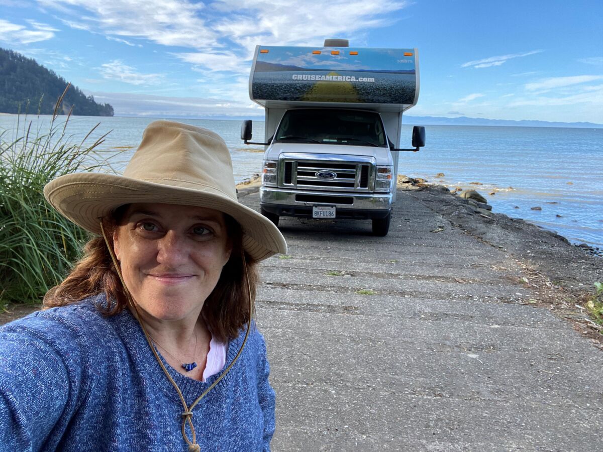 Sharon Whitley poseert voor een camper bij een meer.