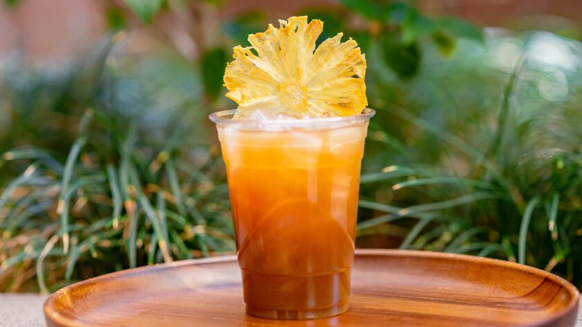 An orange-colored drink called Pride Rock Punch available at Disneyland Park is garnished with a flower.