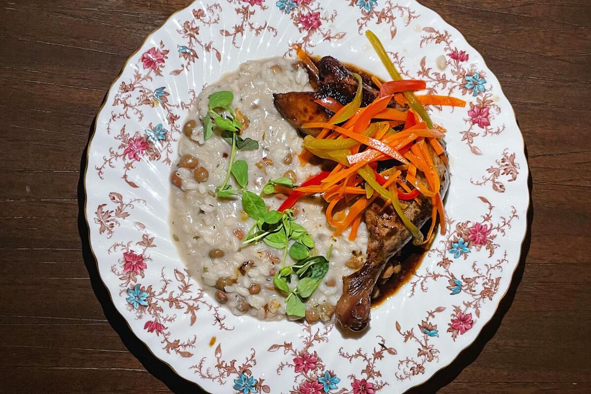 A plate of jerk chicken with risotto garnished with pickled carrots and peppers.
