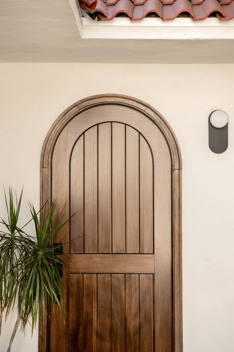 The custom-made front door of the main home is wood with an arched top.