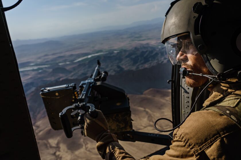 KANDAHAR, AFGHANISTAN -- MAY 6, 2021: A UH-60 Blackhawl gunner surveys the terrain out the window during a resupply flight towards an outpost in the Shah Wali Kot district north of Kandahar, Afghanistan, Thursday, May 6, 2021. The Afghan Air Force, which the U.S. and its partners has nurtured to the tune of $8.5 billion since 2010, is now the governmentOs spearhead in its fight against the Taliban. Since May 1, the original deadline for the U.S. withdrawal, the Taliban have overpowered government troops to take at least 23 districts to date, according to local media outlets. That has further denied Afghan security forces the use of roads, meaning all logistical support to the thousands of outposts and checkpoints N including re-supplies of ammunition and food, medical evacuations or personnel rotation N must be done by air. (MARCUS YAM / LOS ANGELES TIMES)