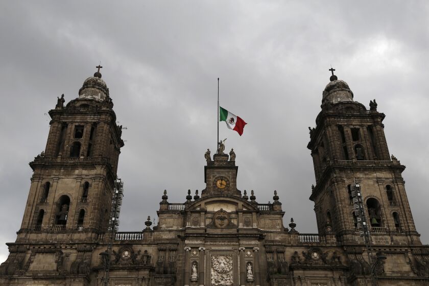 FILE - The Mexican national flag flies at half-mast on top of the Metropolitan Cathedral of Mexico City, Sept. 9, 2017. During the reconstruction work on the Cathedral which was damaged in the 2017 earthquake, workers found in the central dome, small lead boxes containing religious objects, the government reported on Friday, Jan. 27, 2023. (AP Photo/Marco Ugarte, File)