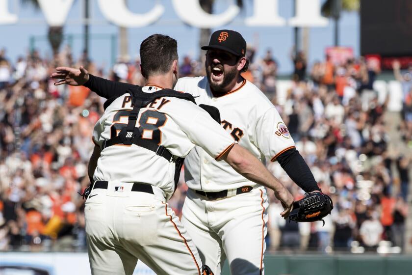 San Francisco Giants closing pitcher Dominic Leone, right, and San Francisco Giants catcher Buster Posey (28) react after defeating the San Diego Padres in a baseball game in San Francisco, Sunday, Oct. 3, 2021. The Giants won 11-4. (AP Photo/John Hefti)