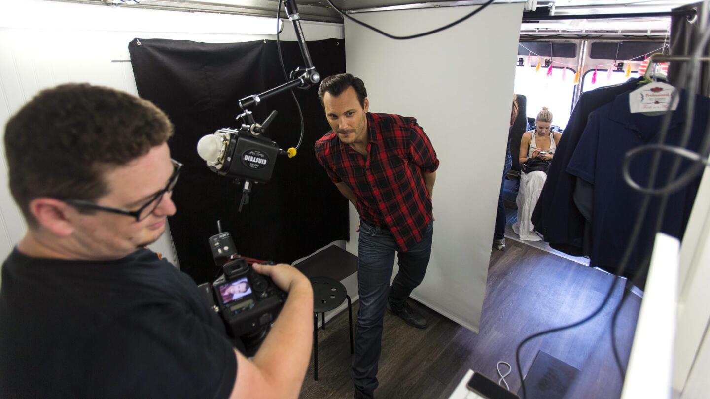 Actor Mark Gantt, center, looks at photo shoot results with photographer Adam Hendershott inside the Headshot Truck during its grand opening in July.