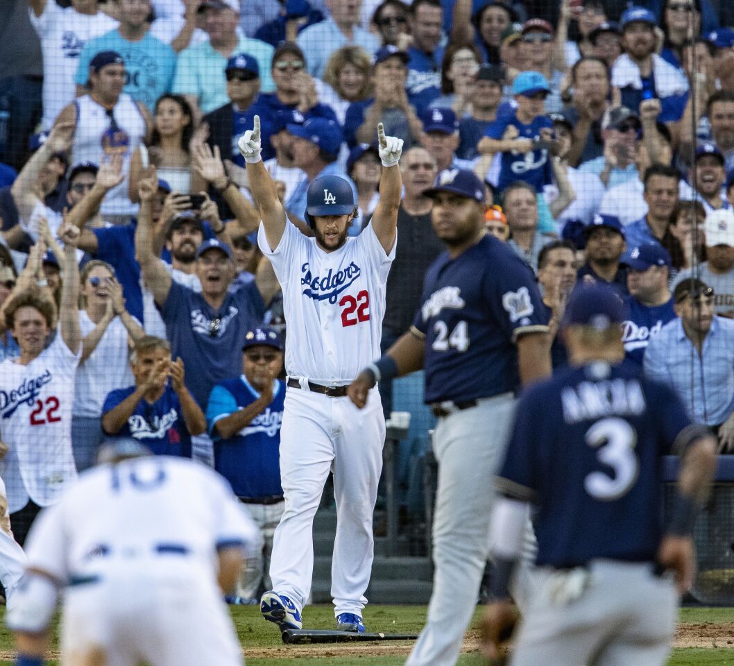 Dodgers starting pitcher Clayton Kershaw raises his arms after scoring on a double by Justin Turner in the seventh inning.