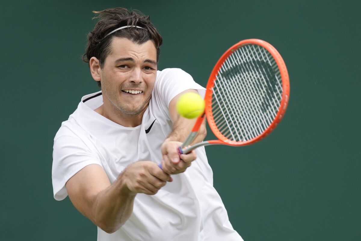 Taylor Fritz of the US plays a return to Steve Johnson of the US during the men's singles second round match on day four of the Wimbledon Tennis Championships in London, Thursday July 1, 2021. (AP Photo/Kirsty Wigglesworth)