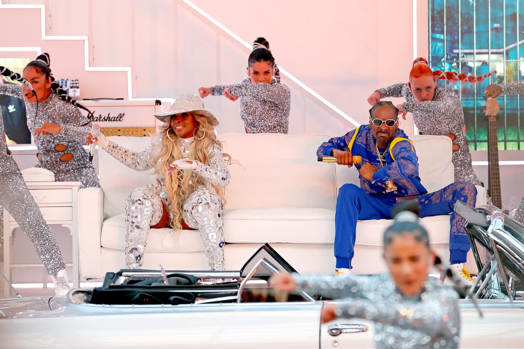 Mary J. Blige and Snoop Dogg on a white stage surrounded by backup dancers.