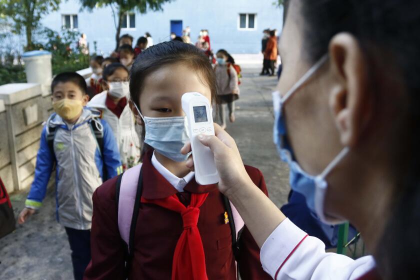 FILE - A teacher takes the body temperature of a schoolgirl to help curb the spread of the coronavirus before entering Kim Song Ju Primary School in Central District in Pyongyang, North Korea, on Oct. 13, 2021. According to North Korea, its fight against COVID-19 has been impressive: About 3.3 million people have been reported sick with fevers, but only 69 have died. (AP Photo/Cha Song Ho, File)