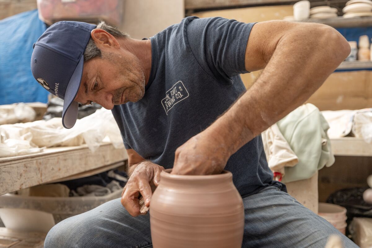Michael Totah, founder and owner of The Wheel Stoneware, forms clay into a vase on a potter's wheel.