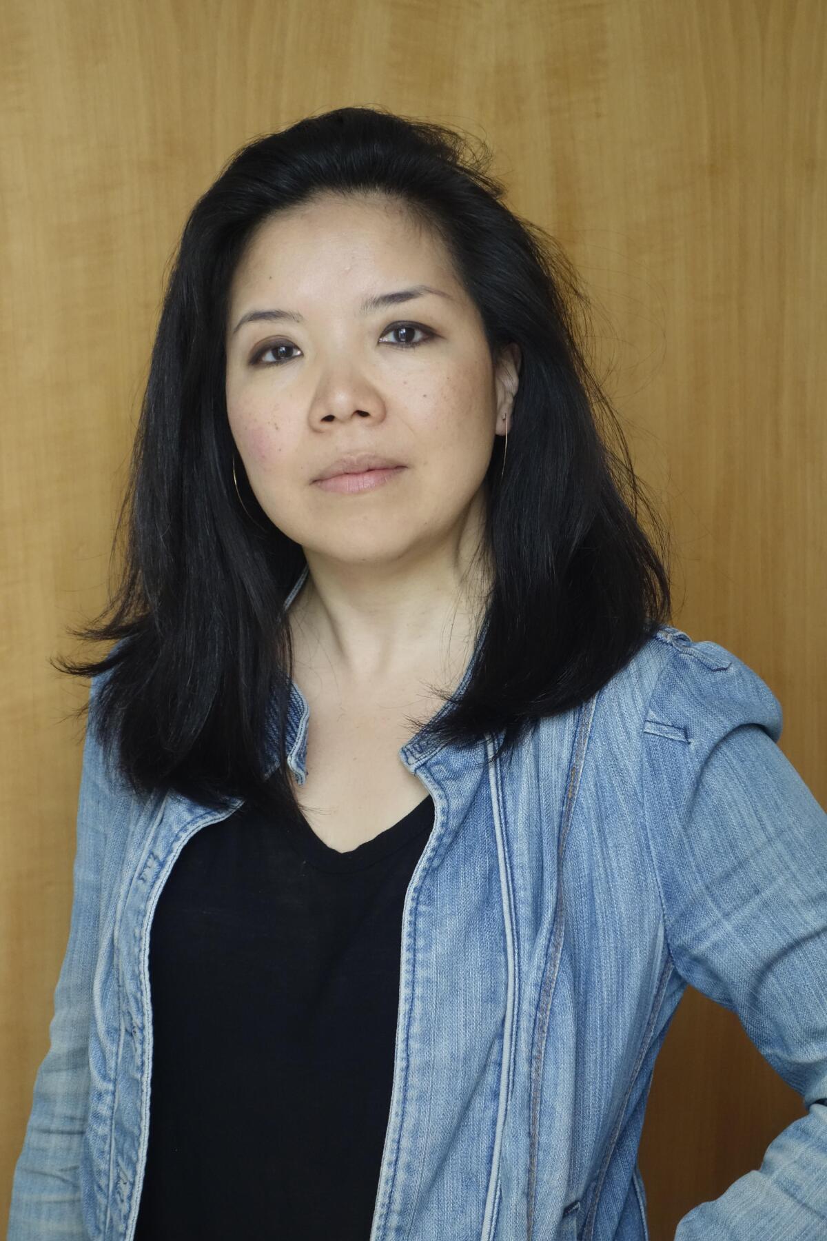 A woman with shoulder-length dark hair in a blue shirt over a black T-shirt.