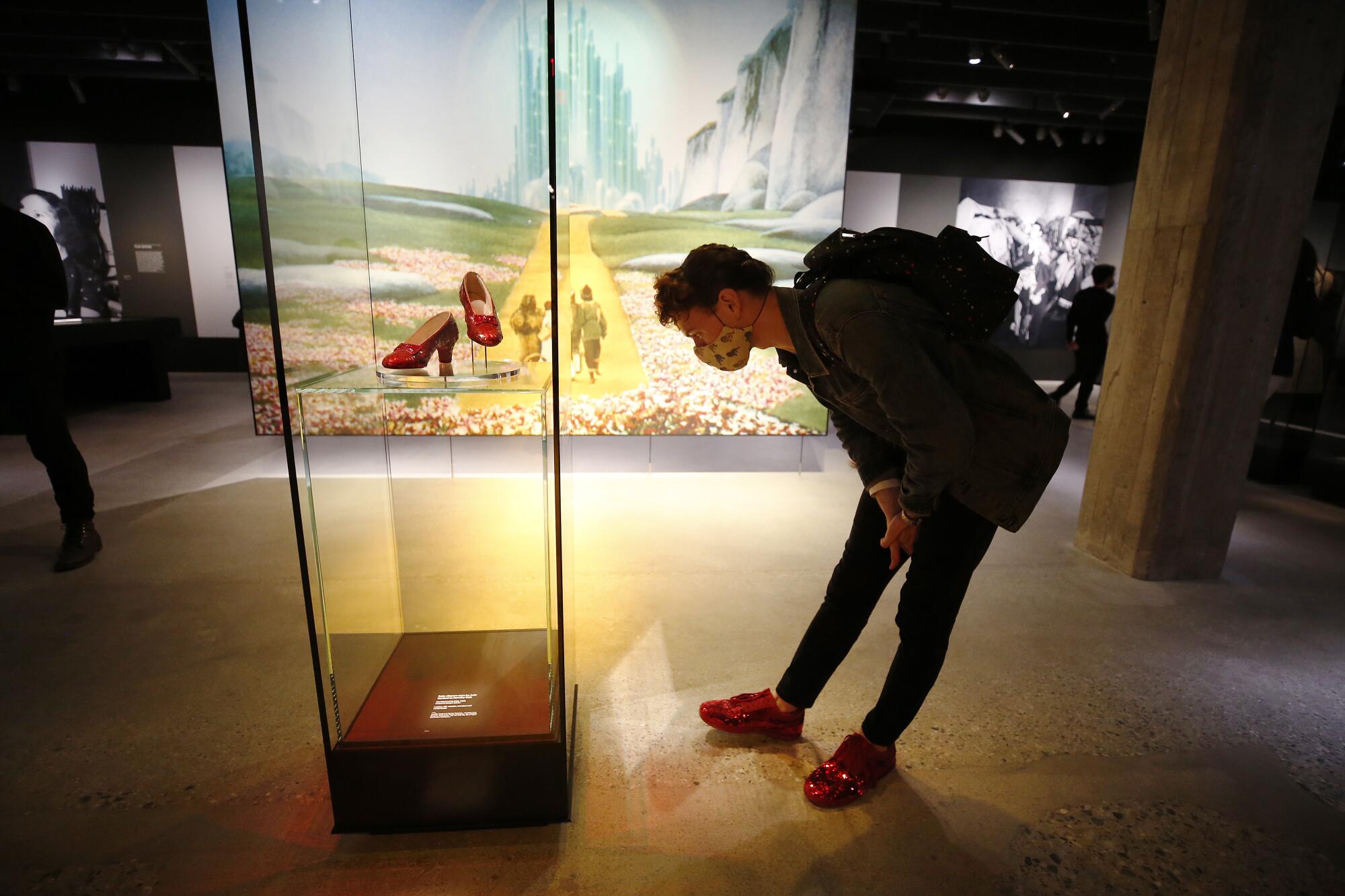 A person bends to look at a display case containing Dorothy's ruby slippers from "The Wizard of Oz."