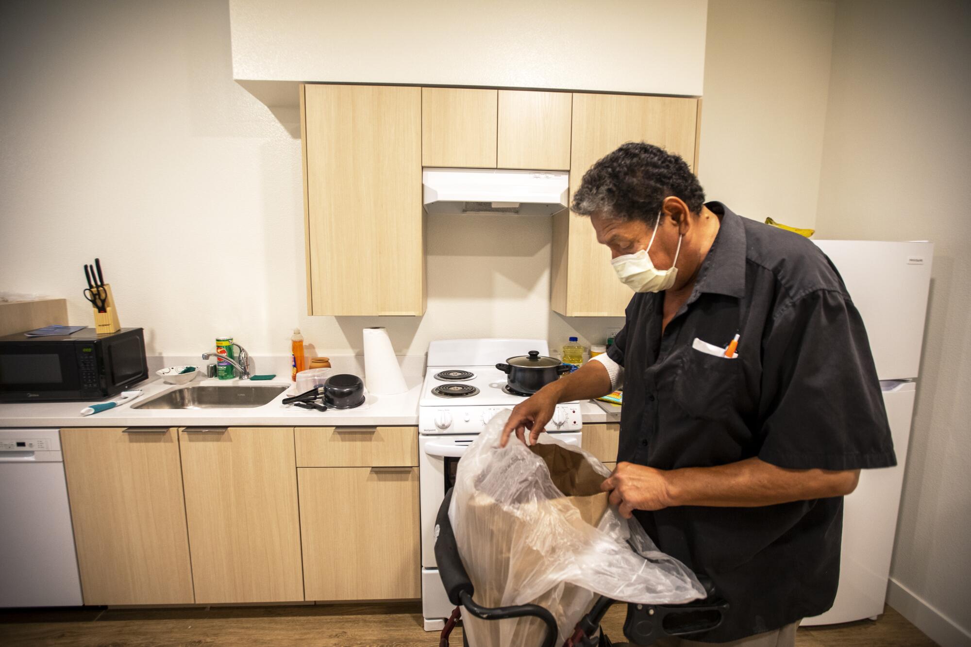Angel Martinez puts away groceries inside his new home at Washington View Apartments in Los Angeles.