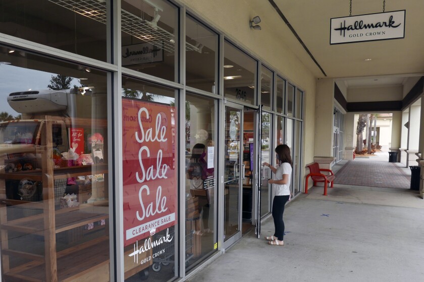 A sale sign is displayed near the entrance of a Hallmark store Tuesday, Jan. 12, 2021, in Orlando, Fla. Retail sales fell for a third straight month, as a surge in virus cases kept people away from stores and restaurants during the holiday shopping season. The report released Friday is yet another sign that the pandemic is slowing the U.S. economy. Last month, the country lost jobs for the first time since the spring.(AP Photo/John Raoux)