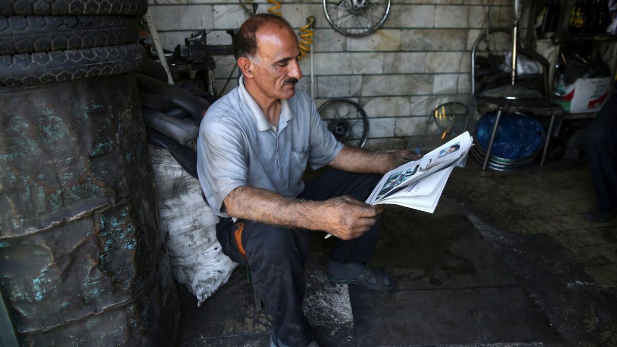 A motorcycle repairman reads a newspaper at his shop near Iran's parliament building in Tehran on May 8, 2017.