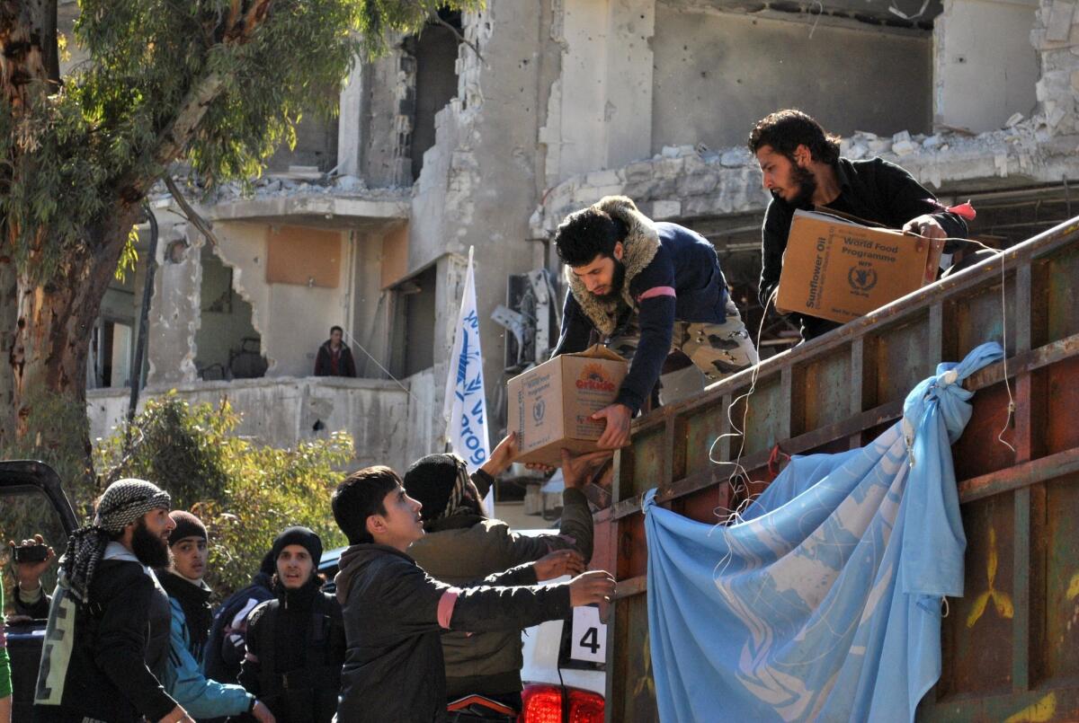 Rebel fighters help unload aid food during a U.N.-led humanitarian operation in the besieged Syrian city of Homs.