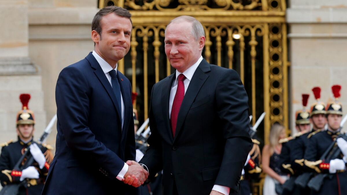 Russian President Vladimir Putin, right, is welcomed by French President Emmanuel Macron at the Palace of Versailles near Paris on May 29, 2017.