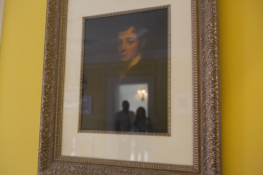Jamie and Frantz Arty are reflected in a portrait of the original homeowner.