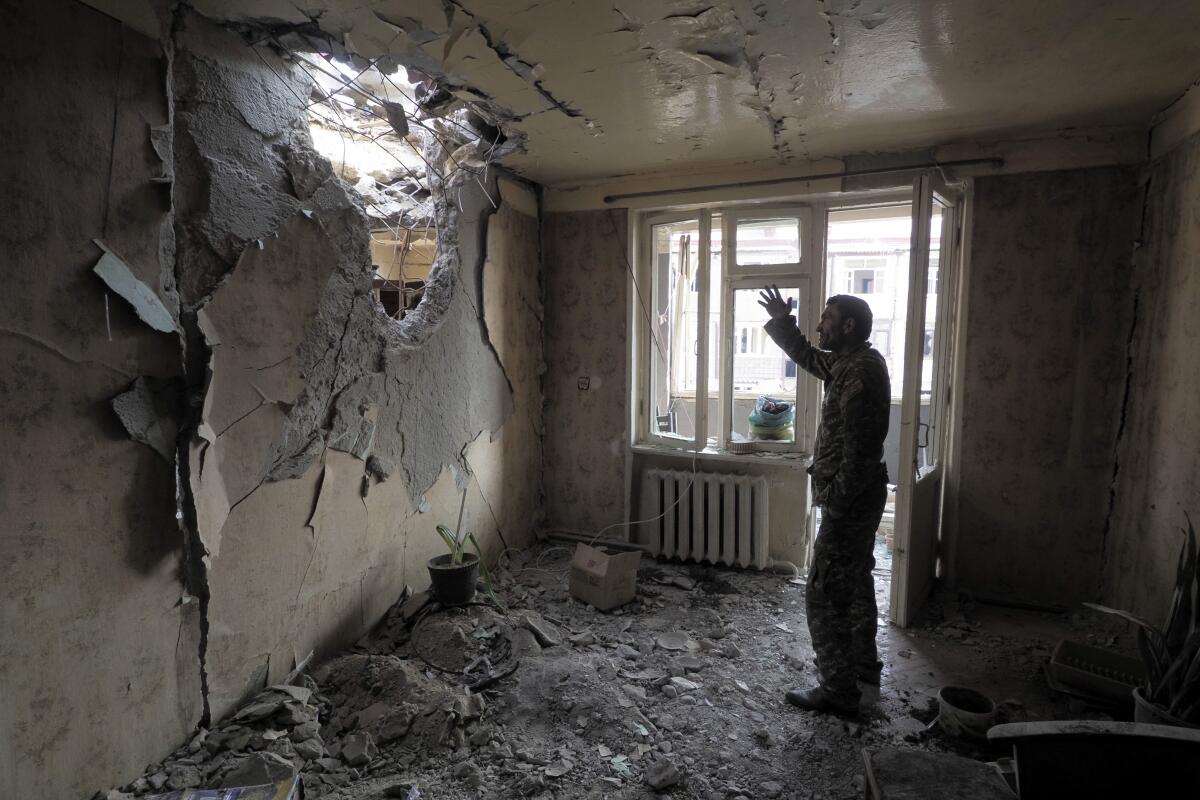 A man gestures in an apartment damaged by shelling by Azerbaijan's artillery in Stepanakert, Nagorno-Karabakh.