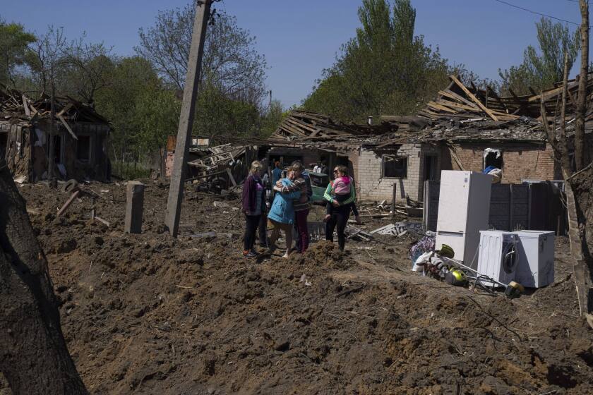 People react as they stand next to a crater in destroyed residential area after Russian airstrike in Bakhmut, Donetsk region, Ukraine, Saturday, May 7, 2022. (AP Photo/Evgeniy Maloletka)