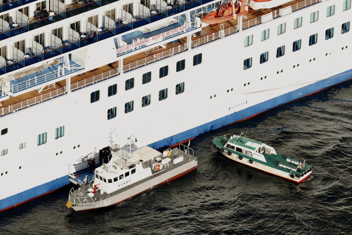 A Japanese coast guard patrol boat, left, ties up alongside the cruise ship Diamond Princess to take passengers who tested positive for the coronavirus to hospitals off Yokohama on Wednesday.