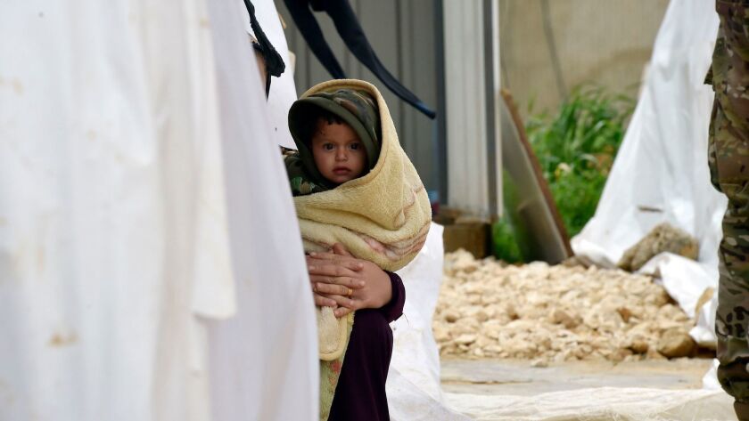 A woman holds a child in a Syrian refugee camp in Lebanon's Bekaa Valley on Dec. 10.