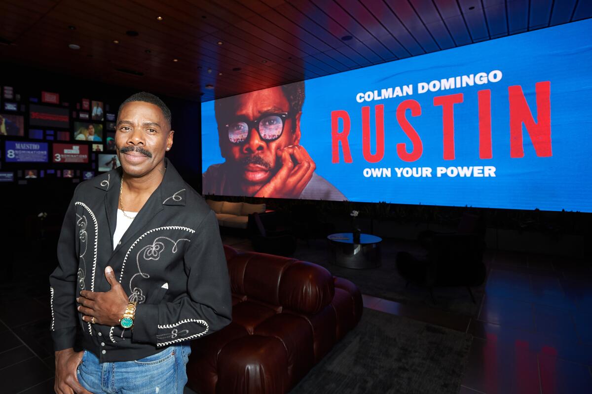 Colman Domingo stands next to a sign that says 'Rustin'