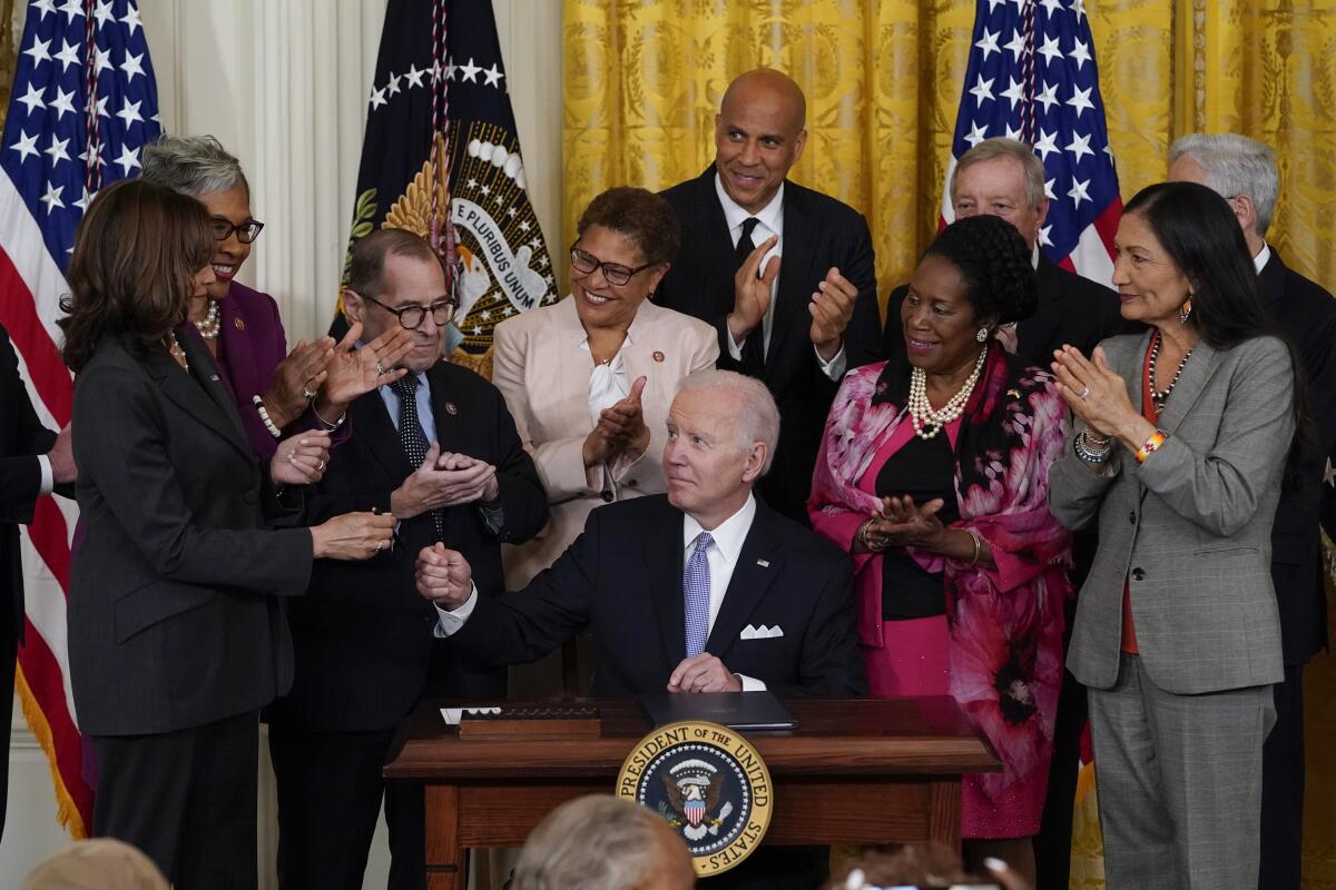 President Biden looks at Vice President Kamala Harris as supporters applaud him after signing an order