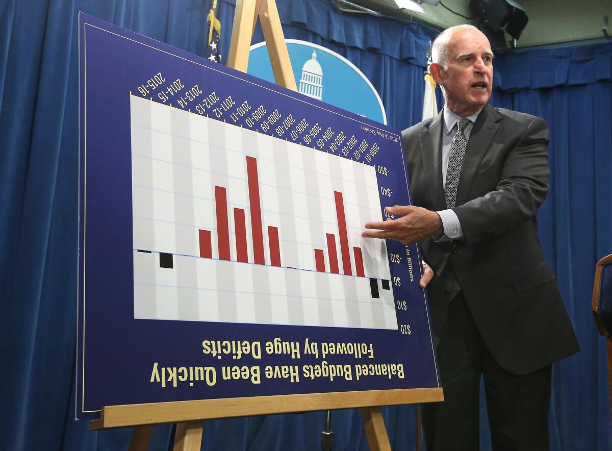 Gov. Jerry Brown jokes with reporters by turning a budget chart upside as he discusses his revised state budget plan during a news conference in Sacramento on May 14.