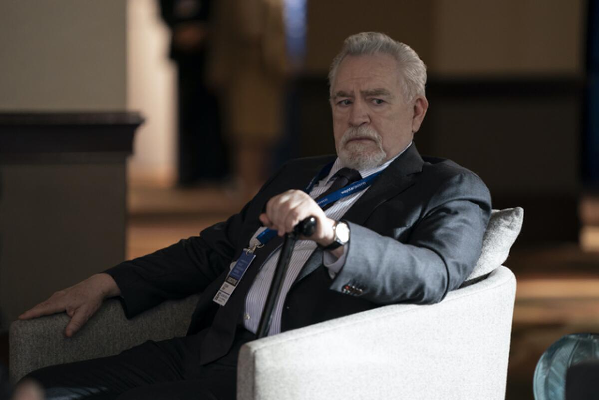 An older man in a suit and tie sits in a chair in "Succession." 