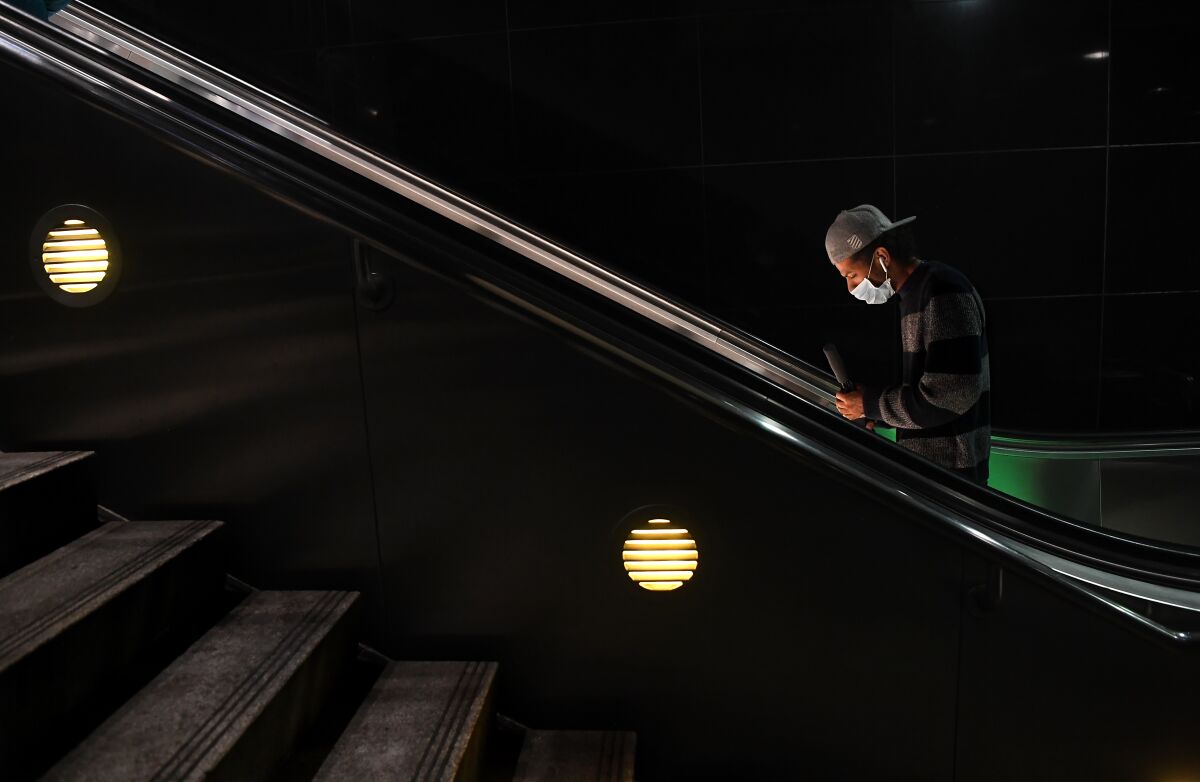 A man wears a mask on an escalator