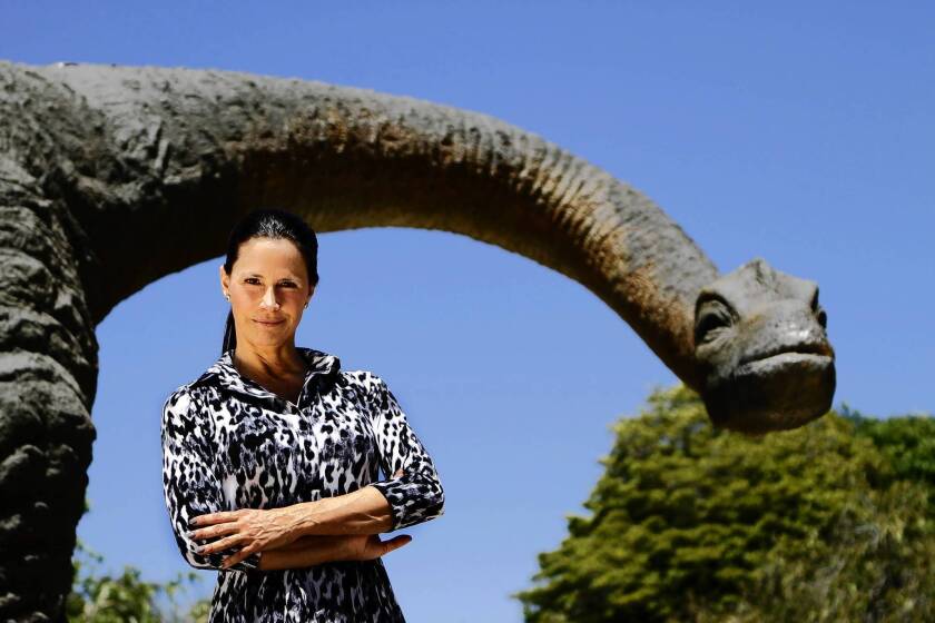 Carolyn Franks, owner of the Zoomars petting zoo on historic Los Rios Street in San Juan Capistrano, stands in front of Juan the Capistrano Dinosaur. Detractors say the 40-foot apatosaurus statue is an eyesore that has no place in the city, and Juan is scheduled to be shipped to a tourist attraction in Arizona.