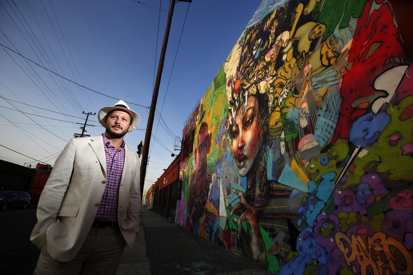 Daniel Lahoda stands in front of a mural by David Choe (Los Angeles) and Aryz (Spain) at Southwest corner of 7th and Mateo streets in Los Angeles. The mural is part of his LA Freewalls project, which has put over 100 murals in Los Angeles, mostly in the Arts District.