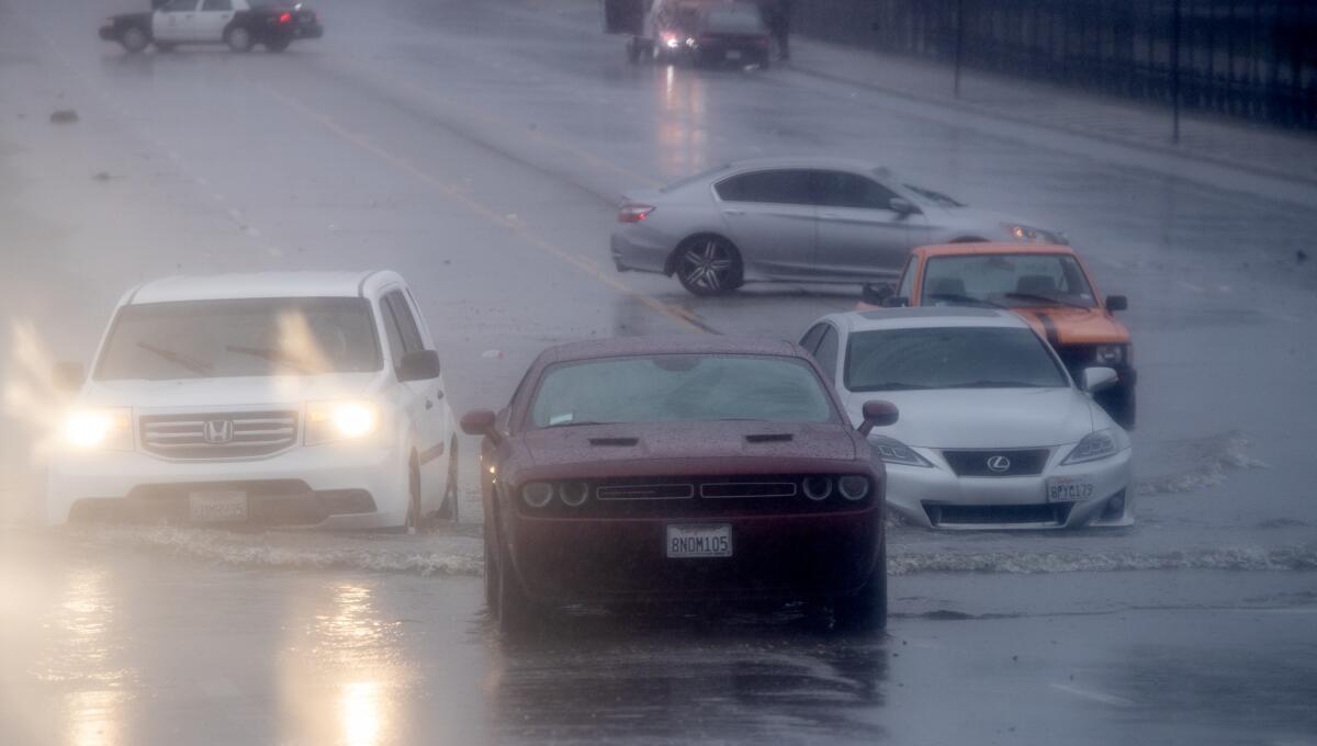 Vehicles driving through a flooded area near the Hollywood Burbank Airport during heavy rain in February 2023.