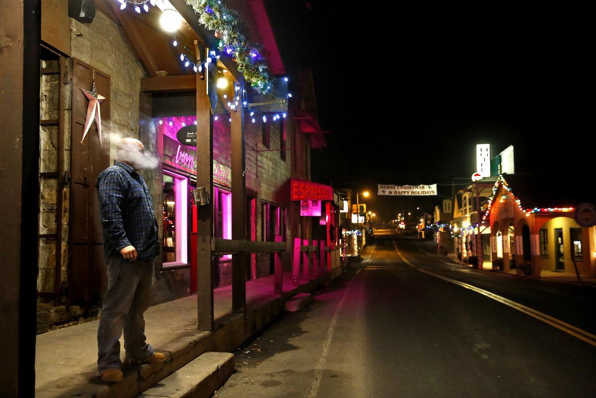 On a chilly December night, a patron takes a smoke break outside the Iron Door Saloon in Groveland, Calif. It's Karaoke Night at the 118-year-old landmark but the saloon is all but empty of locals. "I think everyone is just feeling a little whipped," said bartender Johnny Owens.