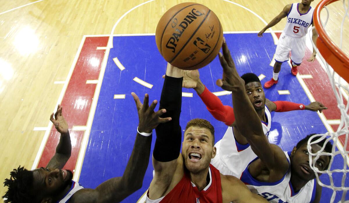 Clippers' Blake Griffin shoots over 76ers defenders during the Clippers' 119-98 win over Philadelphia to clinch a spot in the playoffs.