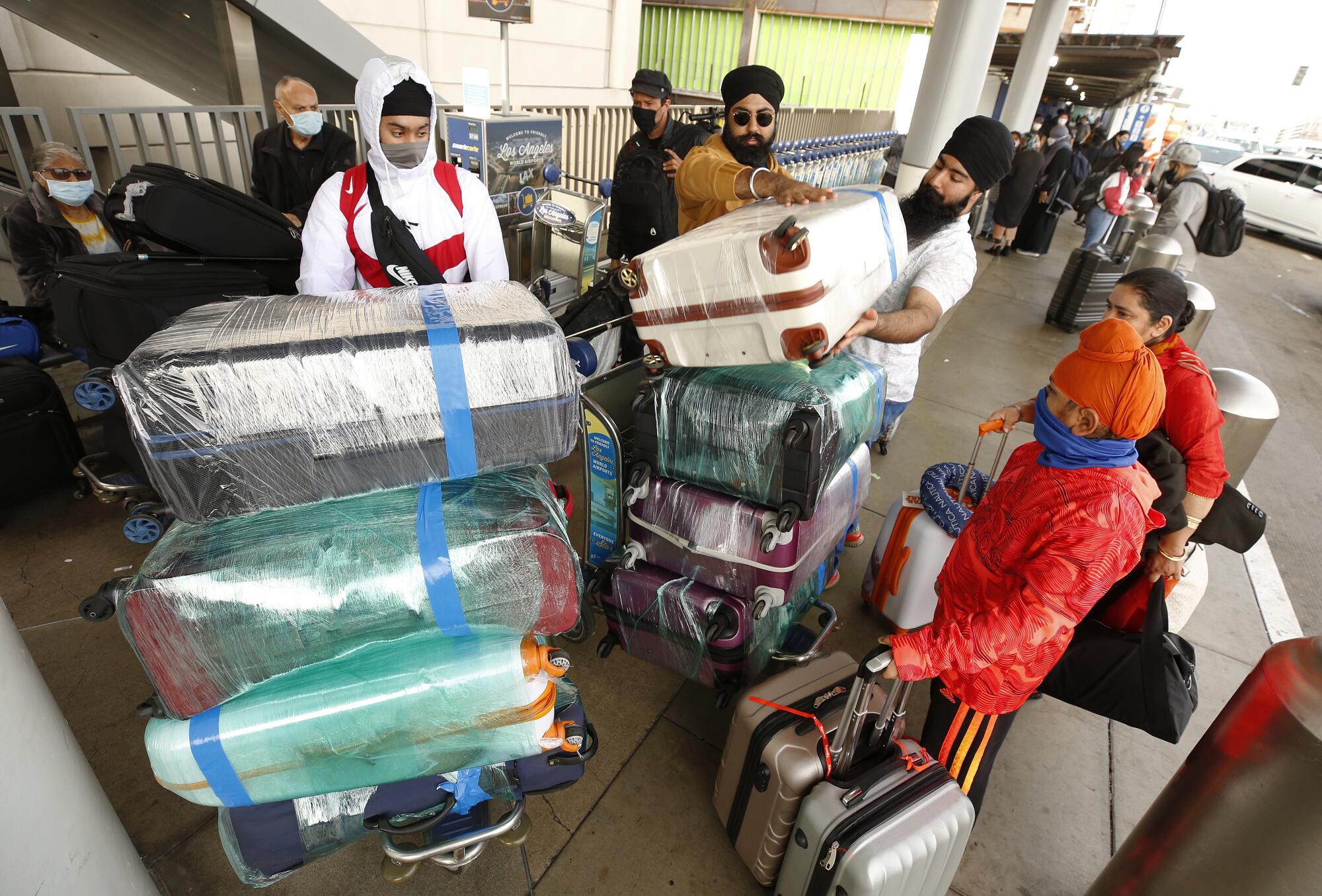 Rubal Singh, center, stacks bags with his family as they prepare to travel to India 