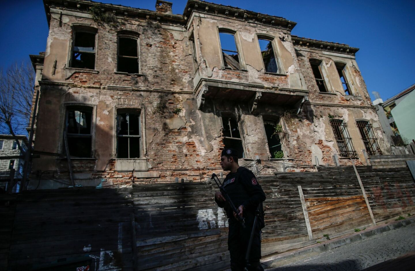 A Turkish police officer patrols past a derelict building in Istanbul's tourist hub of Sultanahmet after a blast killed at least 10 people.