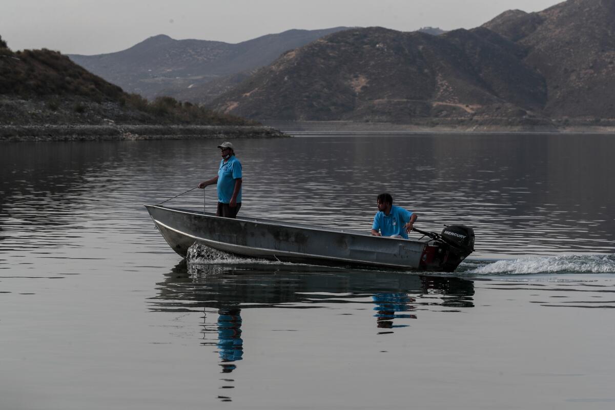 Two people ride on a motorboat in a lake.