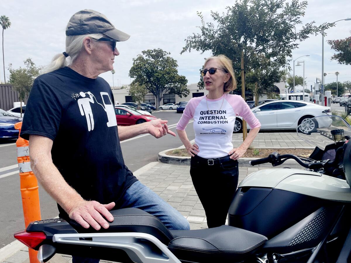 A man with a motorcycle talks with a woman