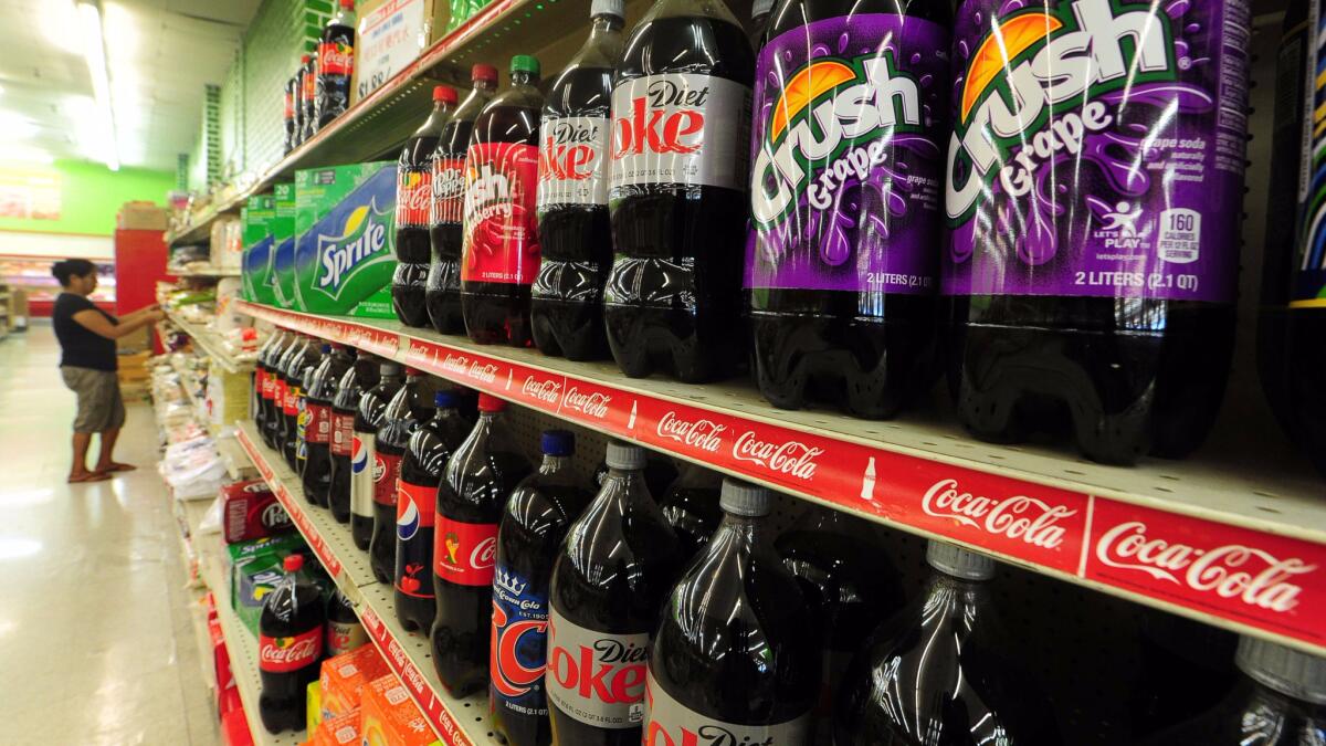 Sodas and other sugar-sweetened beverages sit on store shelves in a grocery store.