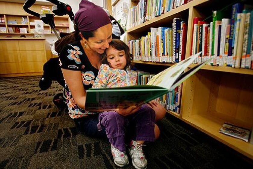 Ortal Klyman reads to her daughter, Leeyah, 2, at the Jewish Community Library on Wilshire Boulevard. The facility is considering moving much of its collection to the American Jewish University on Mulholland Drive in Bel-Air.