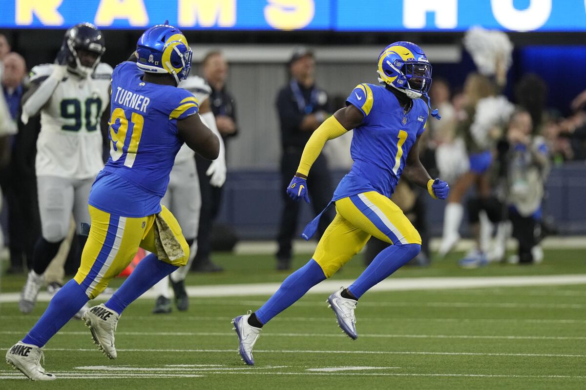 Rams defensive tackle Kobie Turner (91) celebrates after cornerback Derion Kendrick (1) intercepted a pass.