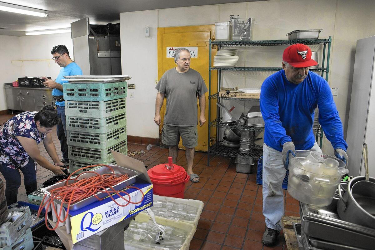 Owner Elia Challita, center, looks on as he sells what's left of the kitchen supplies at Arnie's Manhattan Restaurant and Deli in Newport Beach on Friday.